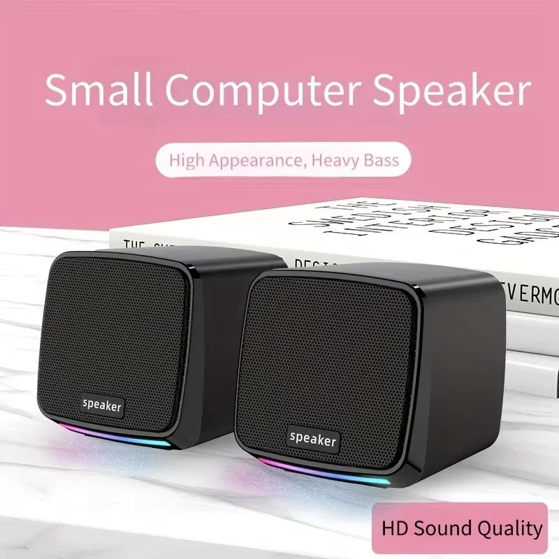 Mini speaker with colorful lights on a desk next to a laptop