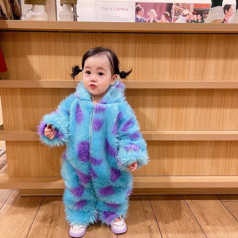Adorable baby in a hooded animal-print jumpsuit lying on a soft blanket